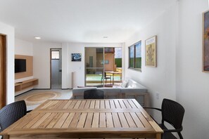 Un intérieur moderne avec une table en bois, des chaises noires, un canapé et un téléviseur.