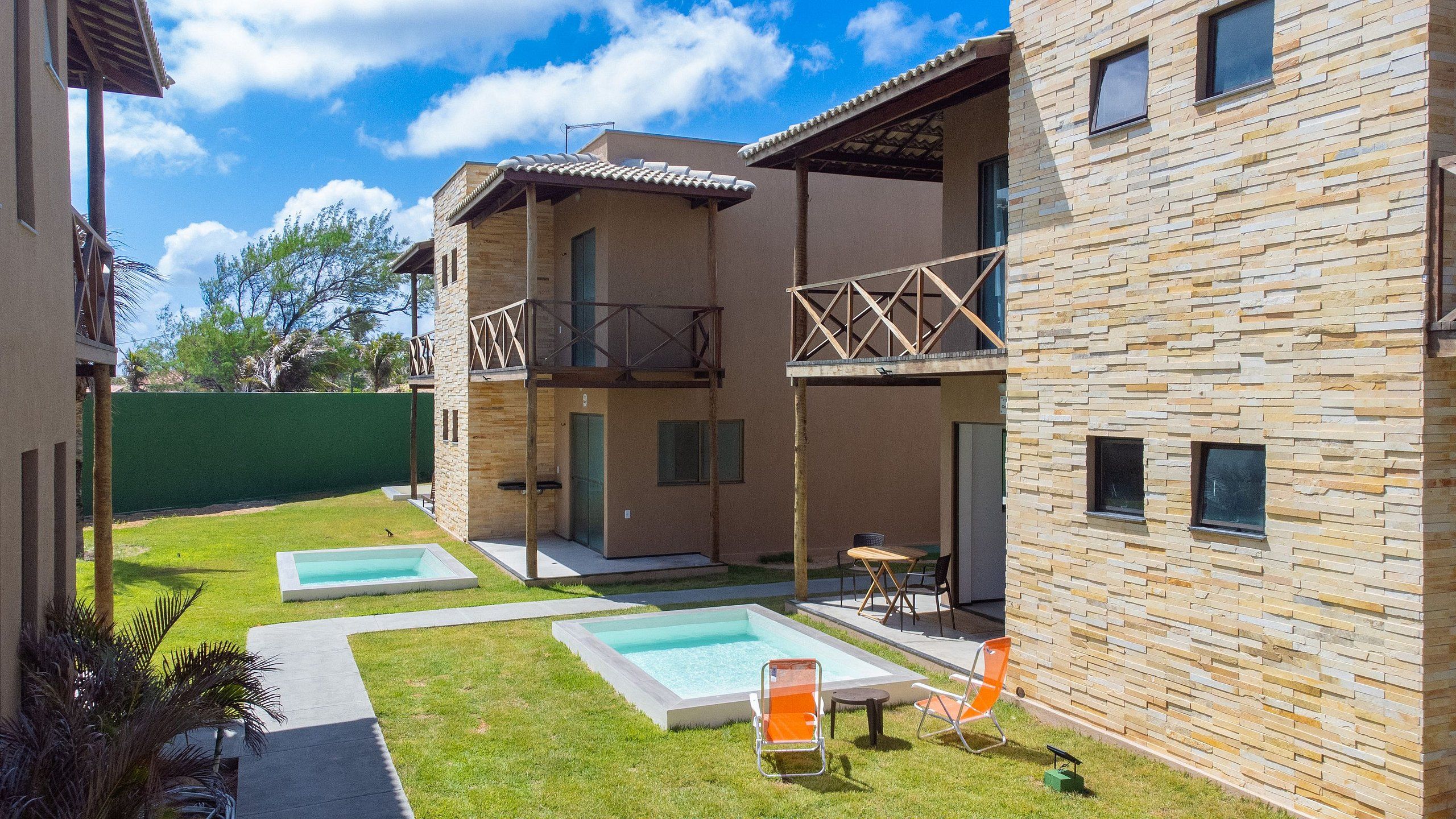 A modern building with a pool area, including two rectangular pools and outdoor seating.