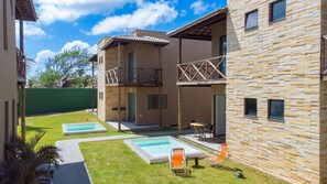 A modern building with a pool area, including two rectangular pools and outdoor seating.