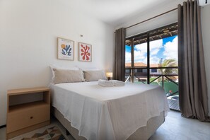 Ein ordentlich bezogenes Bett mit Kissen und einem gefalteten Handtuch, ein Nachttisch und zwei gerahmte Kunstwerke an der Wand.