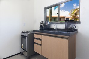 A compact kitchen with a gas stove, a coffee maker, and a sink.
