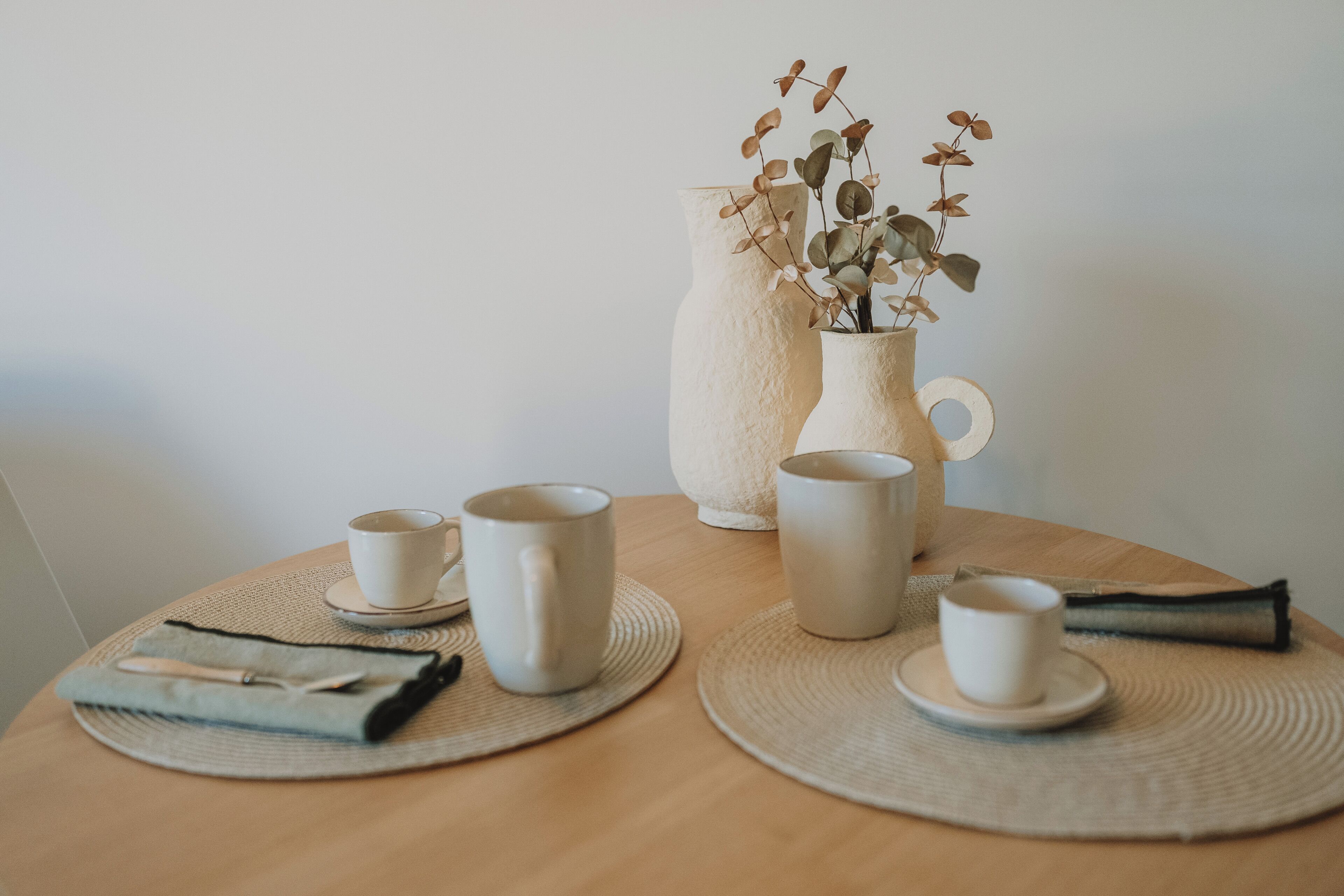 Una mesa con dos jarrones, dos tazas y una servilleta.