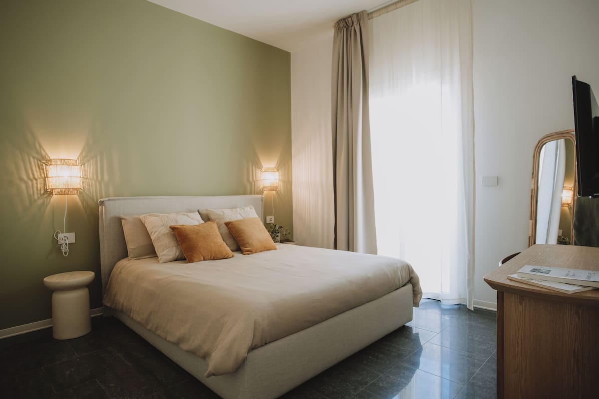 Un dormitorio con cama, lámparas de noche, un espejo y un escritorio de madera.
