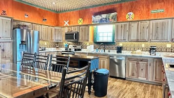 A spacious kitchen with wooden cabinets, a large island with seating, a ceiling fan, and a view of the dining area.