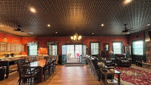 A spacious room with a wooden floor, a dining area with chairs and a table, a seating area with sofas and a rug, and a kitchen with cabinets and a counter. - All Aboard for a stay you wont forget. Trestle View, get your tickets now. (Shenandoah)