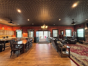 A spacious room with a wooden floor, a dining area with chairs and a table, a seating area with sofas and a rug, and a kitchen with cabinets and a counter. - All Aboard for a stay you wont forget. Trestle View, get your tickets now. (Shenandoah)