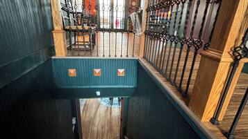 A staircase with wooden railings and metal balusters, leading to a room with a patterned ceiling and a view of the outside.