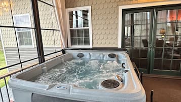 A hot tub with a bench, large windows, and a wooden ceiling.