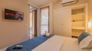 Camera d'albergo con un letto, una TV che mostra Netflix, un telecomando, un armadio e un condizionatore d'aria.