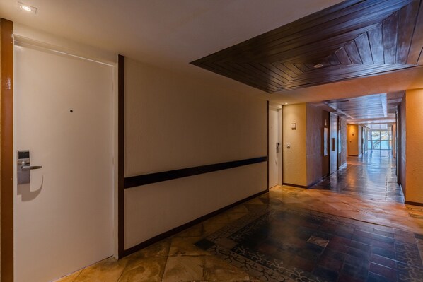 A hallway with a wooden ceiling, a patterned floor, and a door with a handle. - Beach Park Suites #209 - Seafront by Carpediem (Aquiraz)