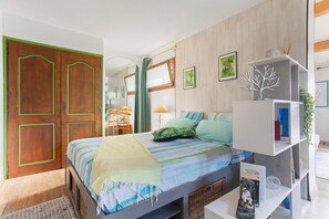 Ein Schlafzimmer mit einem Bett, einem Kleiderschrank, einem Spiegel, einem Regal mit Dekoration und einem Fenster.
