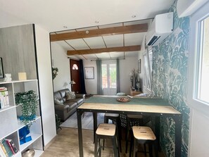 Ein kompakter Wohnbereich mit Essbereich, einer Couch, einem Bücherregal und einem Fenster mit Blick.
