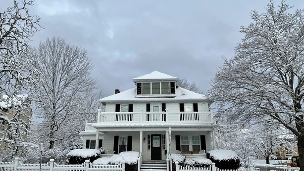 A two-story house with a balcony, a front porch, and a snow-covered landscape. - The Nicholson Inn (Freeport)