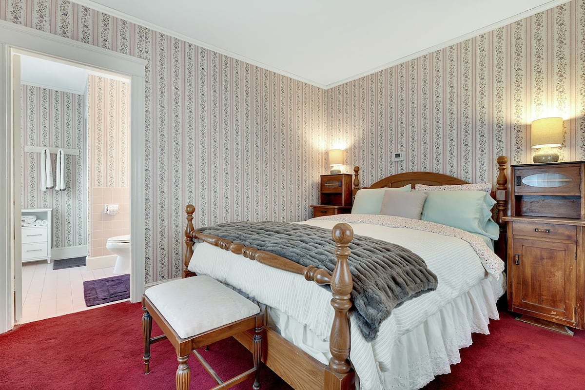 A bedroom with a wooden bed, a nightstand, a lamp, and a wardrobe.