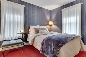 Une chambre à coucher avec un lit, une table de chevet, une lampe et des rideaux.