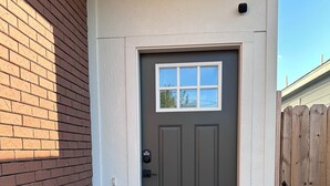 A front door with a keypad lock, a small window above it, and a wooden fence to the right.