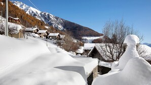 Un village de montagne enneigé, avec ses maisons traditionnelles en bois et un ciel d’un bleu éclatant.