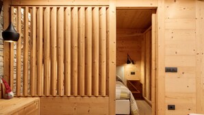 Un intérieur en bois comprenant un lit, une table de chevet, une lampe et une cloison en bois.