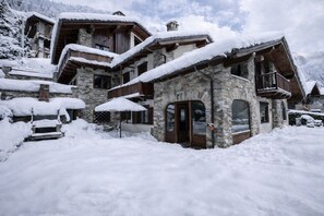 A stone building with a wooden balcony, surrounded by snow.