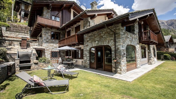 Une maison en pierre dotée d’un balcon, d’un espace extérieur aménagé et d’une cheminée en pierre.