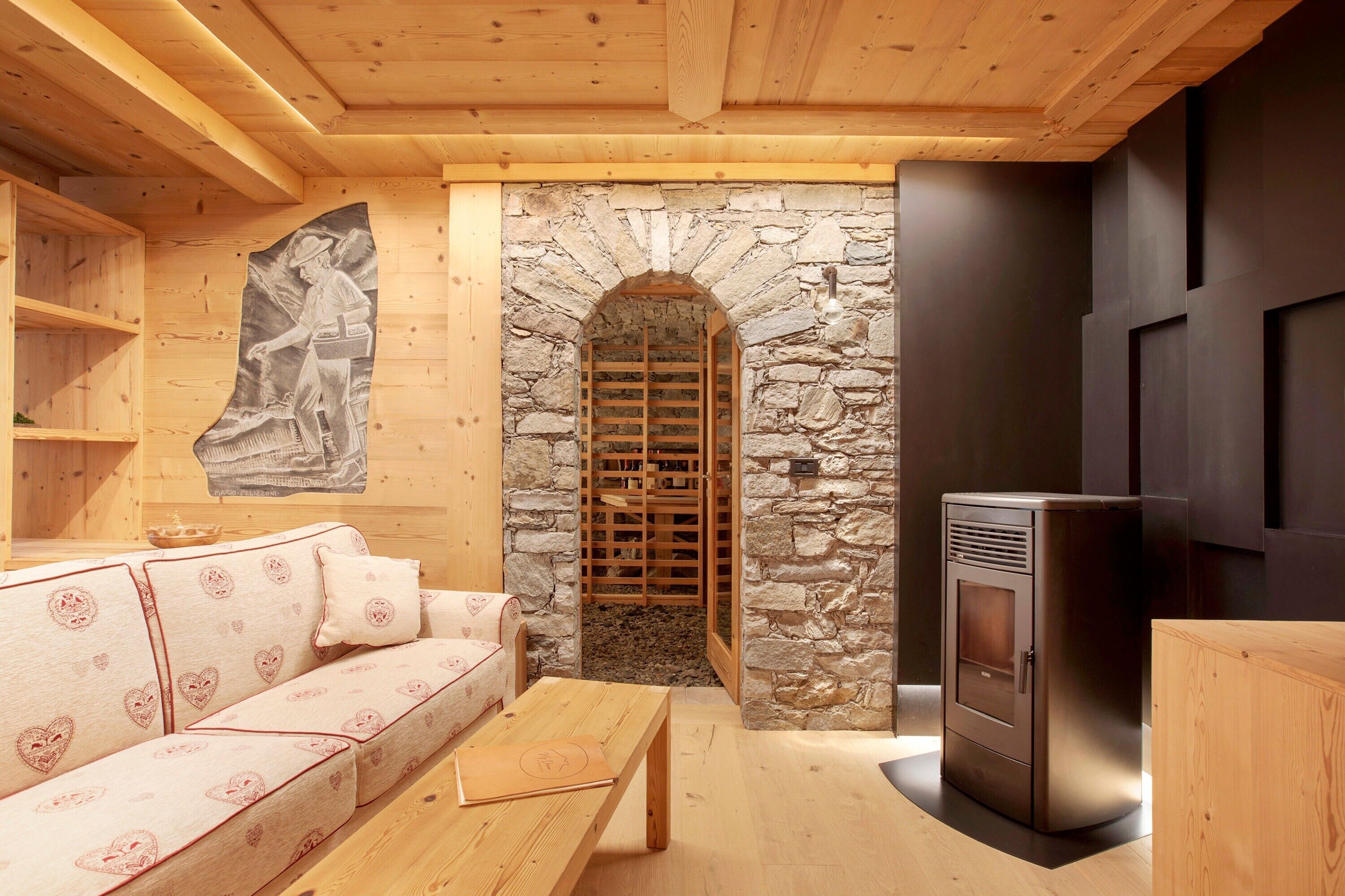 Una habitació acollidora amb una llar de pedra, un sofà amb dibuixos de cor i una taula de fusta.