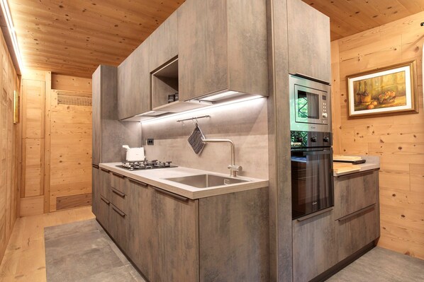 A modern kitchen with wooden cabinetry, stainless steel appliances, and a built-in oven.