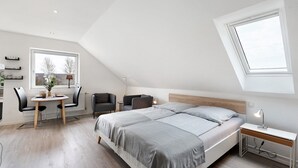 Um quarto com uma cama, mesa de cabeceira, abajur e janela.