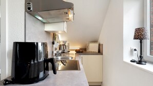 Cozinha moderna com cafeteira, pia e janela com luminária.