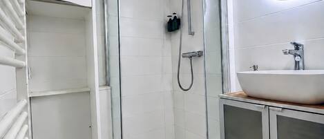 A modern bathroom with a glass-enclosed shower, a white sink, and a mirror.