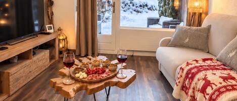 En hyggelig stue med et træbord, et fladskærms-tv og en sofa med et rødt tæppe.