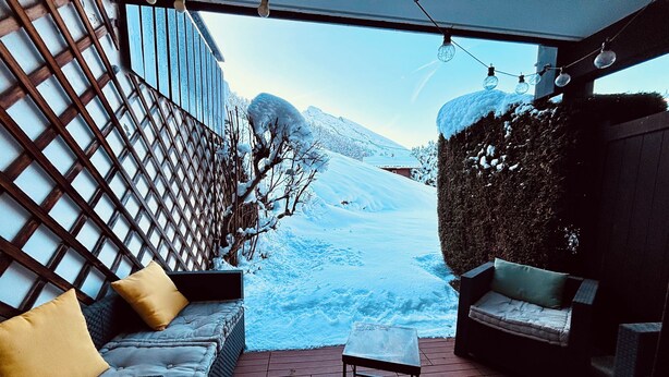 Uma área de estar coberta ao ar livre com vista para uma paisagem nevada.