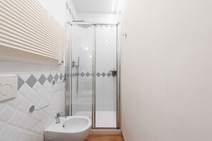 Ein Badezimmer mit Duschkabine aus Glas, einem weißen Waschbecken und einem Handtuchhalter.