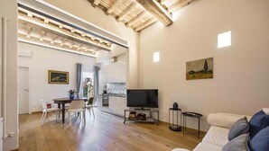 Un saló amb televisió, un sofà i una zona de menjador amb cadires i taula.