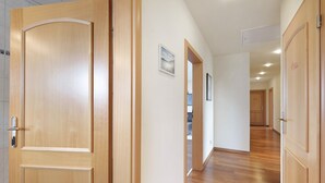 Um corredor com portas de madeira, paredes brancas e chão de madeira.