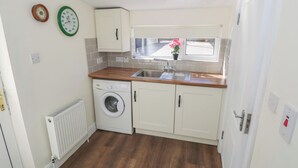 A compact kitchen with a washing machine, a window with a view, and a radiator.