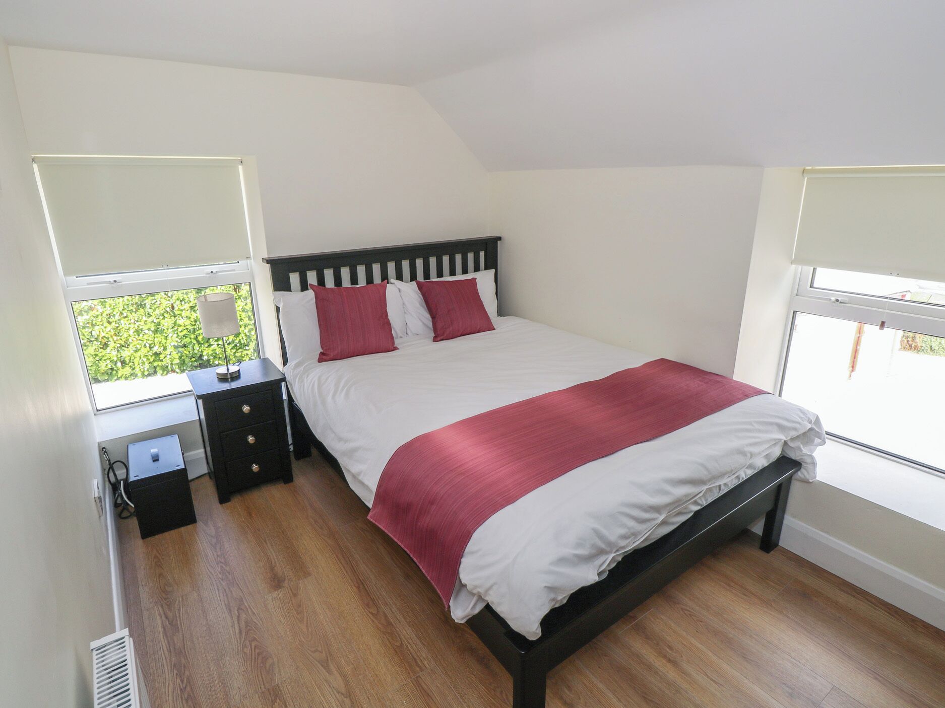A bedroom with a bed, bedside table, and a window.