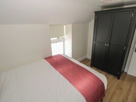 Un dormitorio con cama, armario y ventana.