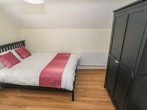 A bedroom with a bed, a radiator, and a wardrobe. - Greenfield House (Cloone)