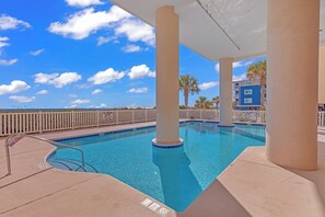 Ein Pool mit blauem Himmel, weißen Säulen und einem weißen Zaun.