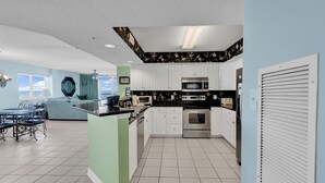 Eine moderne Küche mit weißen Schränken, Edelstahlgeräten und einem Essbereich mit einem blauen Sofa und Tisch.