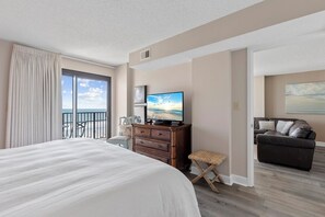 Une chambre d’hôtel dotée d’un grand lit, d’une télévision, d’un balcon avec vue et d’un coin salon comprenant un canapé et une petite table.