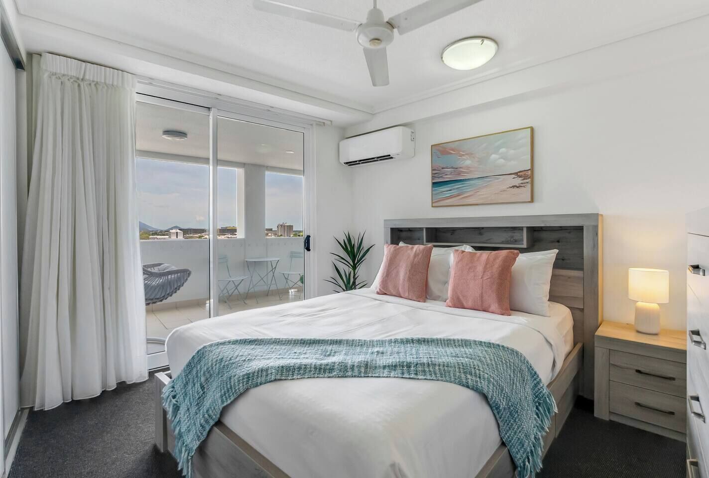 The cosy bedroom features a queen bed, wall-mounted TV, air-conditioning, and direct access to the balcony.