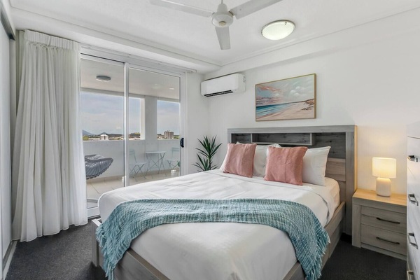 The cosy bedroom features a queen bed, wall-mounted TV, air-conditioning, and direct access to the balcony.