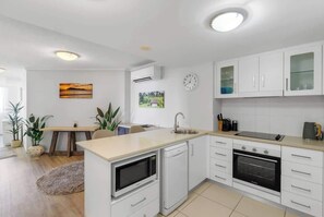 Eine moderne Küche mit weißen Schränken, einem Backofen, einer Mikrowelle und einem Spülbecken.