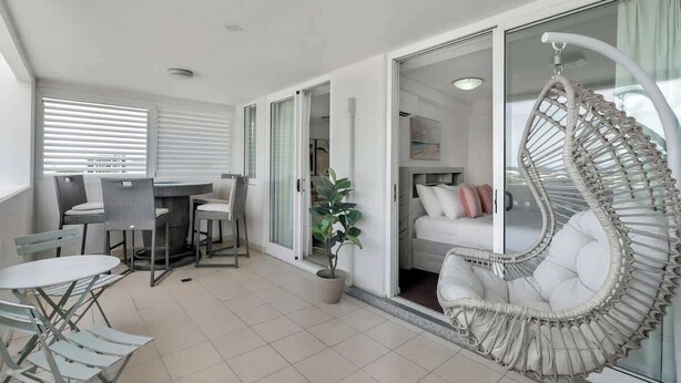 Un intérieur moderne comprenant un coin repas, un espace salon avec un fauteuil suspendu et une chambre dotée d’une porte coulissante.