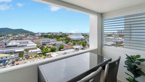 A balcony with a view of a cityscape, including buildings and a mountain. - Peak Studio—Highview Haven across Shopping Centre (Cairns)