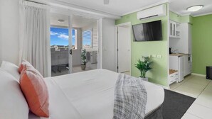 A hotel room with a bed, a desk, a TV, and a balcony with a view. - Peak Studio—Highview Haven across Shopping Centre (Cairns)