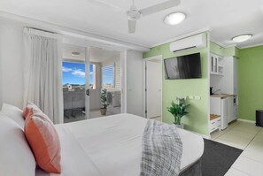 Ein Hotelzimmer mit Bett, Schreibtisch, Fernseher und einem Balkon mit Blick.