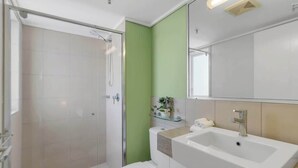 A modern bathroom with a shower, toilet, sink, and a mirror. - Peak Studio—Highview Haven across Shopping Centre (Cairns)