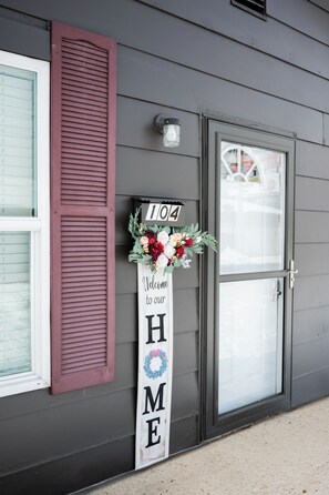 Une maison avec une porte d’entrée, une pancarte de bienvenue et un numéro de maison.